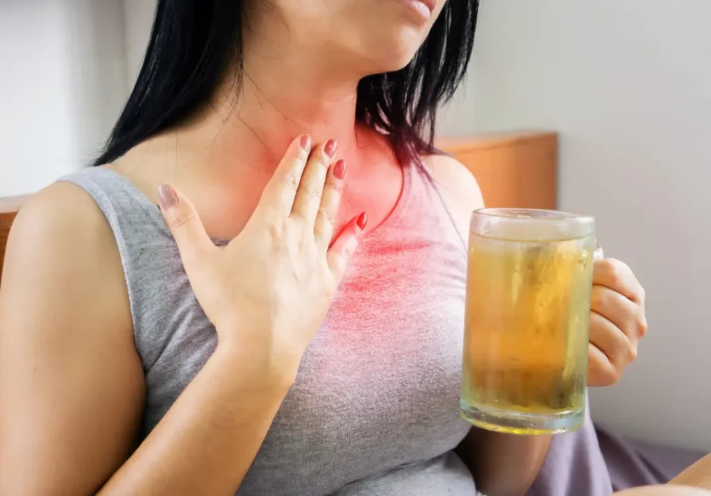 Woman experiencing acid reflux symptoms while holding a cold drink