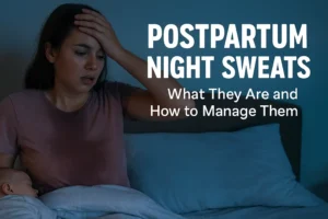 A new mom with postpartum night sweats sits in bed looking flushed and tired, with overlay text that reads “Postpartum Night Sweats – What They Are and How to Manage Them”